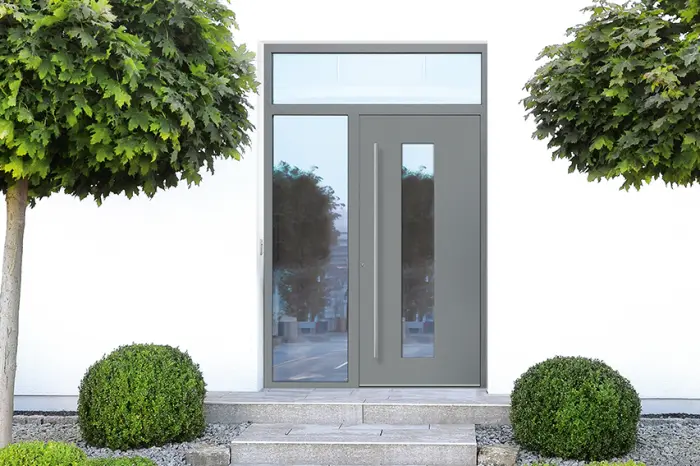 Moderne graue Haustür mit Glasseitenteil und Oberlicht an einem weißen Haus